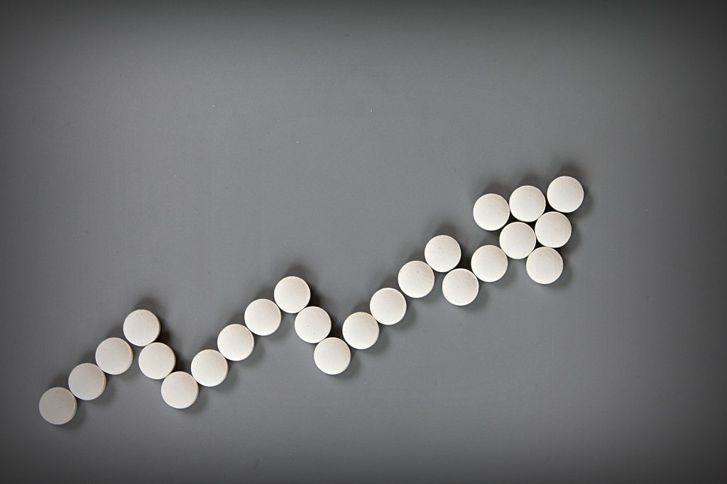 Pills formed into an increasing arrow shape, with a gray background.