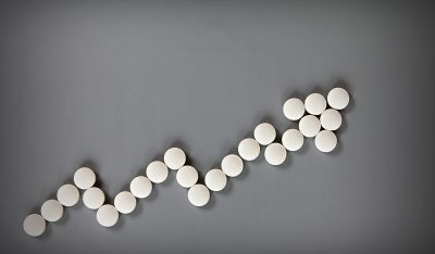 Pills formed into an increasing arrow shape, with a gray background.