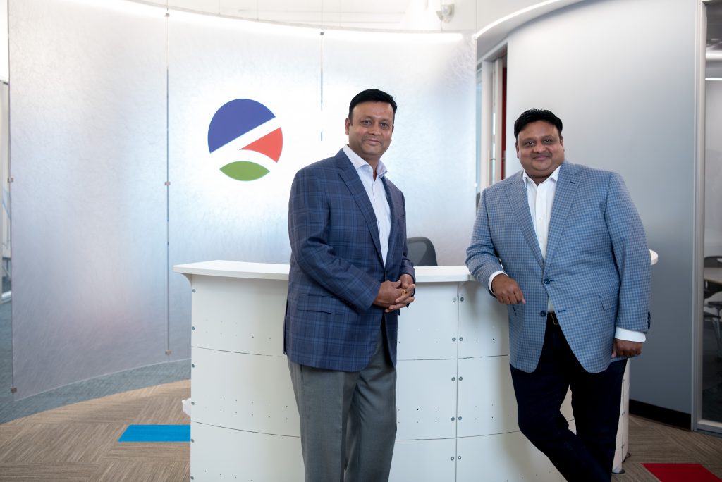 Vikash and Vikram Agrawal standing in front of a desk, with the Levrx logo pictured behind them.